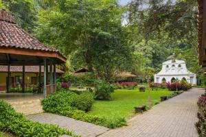 um jardim com um pavilhão e um edifício branco em Villa Lapas Jungle Village em Jacó