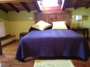 a bedroom with a purple bed with two pillows and a window at Casa Rural Frutos in San Esteban de la Sierra