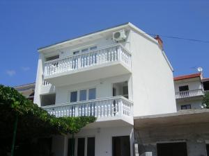 a white building with a balcony on top of it at Judith Apartment in Tisno