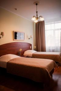 Cette chambre comprend deux lits et un lustre. dans l'établissement Oktyabrskaya Hotel, à Tver