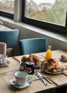 - une table avec des assiettes de viennoiseries et des tasses de jus d'orange dans l'établissement Les Chambres du Haut-Koenigsbourg, à Orschwiller