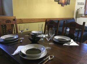 een houten tafel met borden en wijnglazen erop bij Ekhiola in Ochagavía