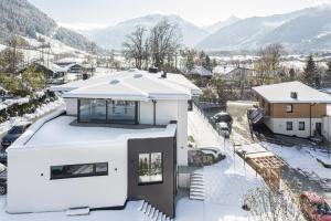 a white house in the snow with mountains in the background at lake and mountains appartements in Maishofen