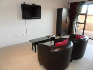 a living room with two leather chairs and a tv at Haus Holzapfel in Beaufort West