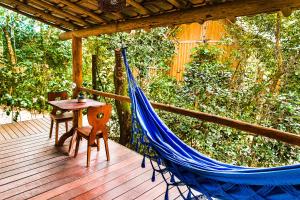 eine Hängematte auf einem Deck mit Tisch und Stühlen in der Unterkunft Pousada Mangue Sereno in Caraíva