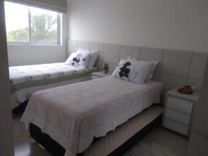 - une chambre avec 2 lits et une fenêtre dans l'établissement Ap Tia Dete Cachoeira, à Florianópolis