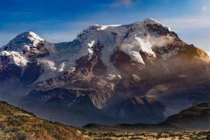 a mountain covered in snow on top of a mountain at Hospedaje San Fernando in Cayambe