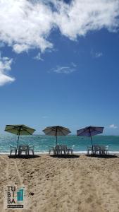 a group of chairs and umbrellas on a beach at Casa Cultural Tubiba Hostel in Tamandaré