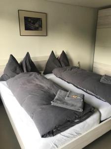 a bed with black and white sheets and pillows at L'ANGOLO DEI SAPORI in Rueun