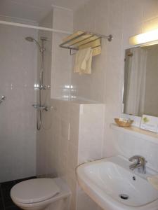 a white bathroom with a toilet and a sink at Hotel de Burg in Domburg