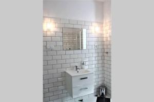 a white tiled bathroom with a sink and a mirror at Corner 5 I Old Town I Cosy Studio in Krakow