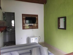 1 dormitorio con cama y pared verde en Siqueira, aluguéis para temporadas, en Paraty