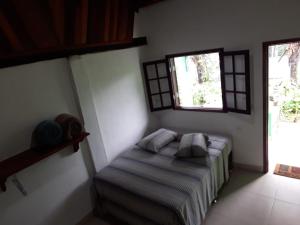 1 dormitorio con 1 cama y 2 ventanas en Siqueira, aluguéis para temporadas, en Paraty