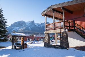 ein Gebäude mit einer Terrasse im Schnee mit Bergen in der Unterkunft Rocky Mountain Ski Lodge in Canmore