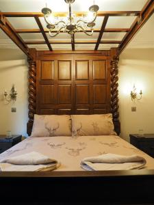 a bed with a wooden head board and a chandelier at Appin House in Fort Augustus