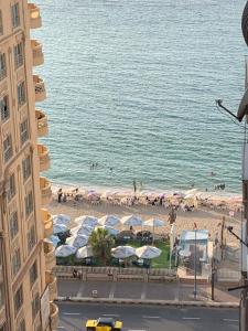 een uitzicht op een strand met parasols en mensen bij mody appartment at alexandria in Alexandrië
