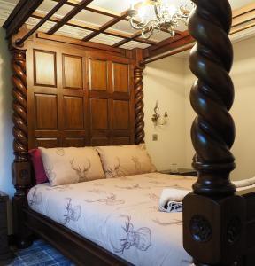 a bedroom with a wooden canopy bed with white sheets at Appin House in Fort Augustus