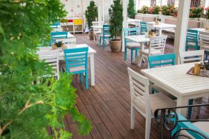 un patio con mesas blancas y sillas azules en Hotel Nove, en Svishtov