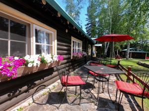 a patio with a table and chairs and an umbrella at Domaine le Bostonnais - Le Village en Bois Rond in La Tuque