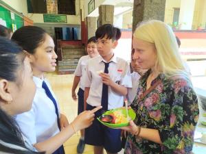a woman holding a plate of food with a group of children at Griya Backpacker Pak yon in Malang +60 photos