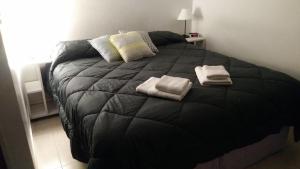 1 dormitorio con 1 cama negra y 2 toallas en Aloha III - El Palomar B&D en El Palomar
