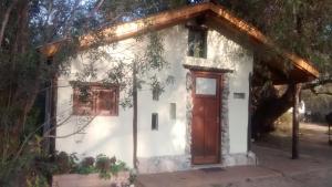 una pequeña casa blanca con una puerta roja en Casita Los Retoños en San Marcos Sierras en San Marcos Sierras
