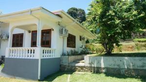 a white house with a porch and a tree at Ogumka, Self catering , Beoliere, Mahe in Victoria