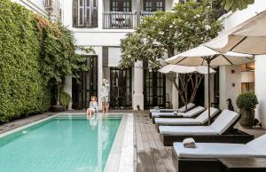 a woman is standing next to a swimming pool at 99 The Heritage Hotel-SHA Extra Plus Certified in Chiang Mai