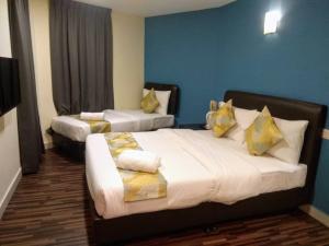 a hotel room with two beds with yellow pillows at Hotel Sunjoy9 @ Mid Valley in Kuala Lumpur