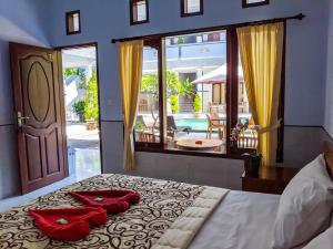 a bedroom with a large bed with red pillows on it at Serangan Inn Mimba in Padangbai
