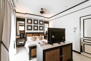 a hotel room with a tv, coffee table, and chairs at 99 The Heritage Hotel-SHA Extra Plus Certified in Chiang Mai