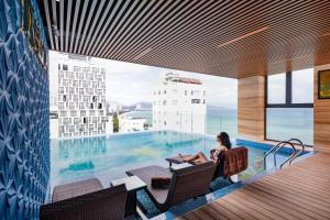 a woman sitting in a chair next to a swimming pool at Nalicas Nha Trang Hotel in Nha Trang