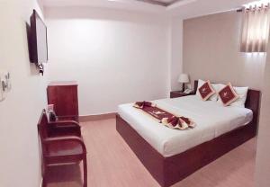 um quarto com uma cama, uma cadeira e uma televisão em Golf Star Hotel em Ho Chi Minh