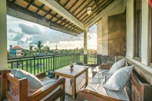 a porch with a couch and a table on a balcony at Three Dewi's Guest House in Ubud