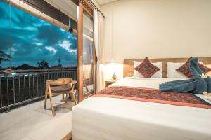- une chambre avec un lit et un balcon avec une fenêtre dans l'établissement Three Dewi's Guest House, à Ubud