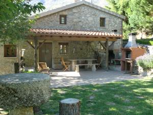a stone house with a wooden pergola in a yard at Quinta Do Circo - Serra Da Estrela - Turismo Rural in Cortes do Meio