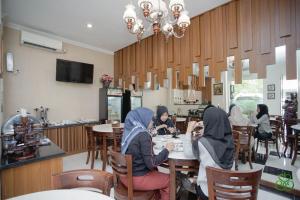 un grupo de personas sentadas en una mesa en un restaurante en Selaras Inn Syariah, en Yogyakarta