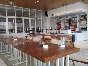 a restaurant with wooden tables and white chairs at Alam Hotel by Cordela in Medan