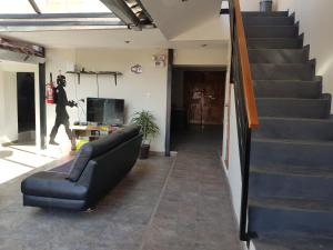 a living room with a couch and a staircase at Xplora Hostel Cusco in Cusco