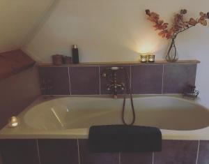 a bath tub in a bathroom with a vase of flowers at Bed & Breakfast Yerseke in Yerseke
