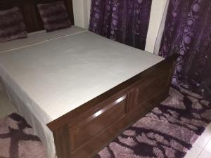 a bed with a wooden frame with a white mattress at Ana Chaves Residence in São Tomé