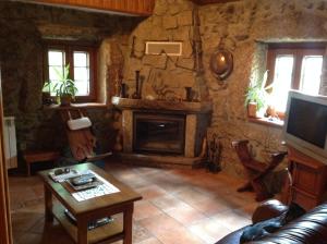 uma sala de estar com uma lareira de pedra e uma televiso em Quinta Do Circo - Serra Da Estrela - Turismo Rural em Cortes do Meio