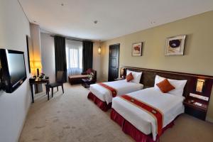 a hotel room with two beds and a flat screen tv at Gino Feruci Kebon Jati by KAGUM Hotels in Bandung