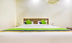 a bedroom with a white bed with green and colorful pillows at Itsy by Treebo - Oasis Inn in Jalandhar