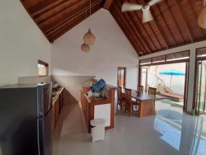 a kitchen and dining room with a table and a refrigerator at Adioga Villa in Ubud