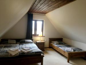 two beds in a attic bedroom with a window at Modryna - Modrzewiowy Dom in Cisna