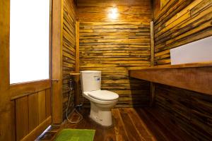 a bathroom with a toilet in a wooden wall at Baan​ Tonlamphu​ Pakpra in Phatthalung