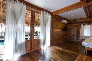 a bedroom with wooden walls and a bed and curtains at Baan​ Tonlamphu​ Pakpra in Phatthalung