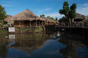 a group of huts with their reflections in the water at Baan​ Tonlamphu​ Pakpra in Phatthalung