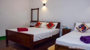 1 dormitorio con 2 camas y espejo en la pared en Woodsy Villa en Sigiriya